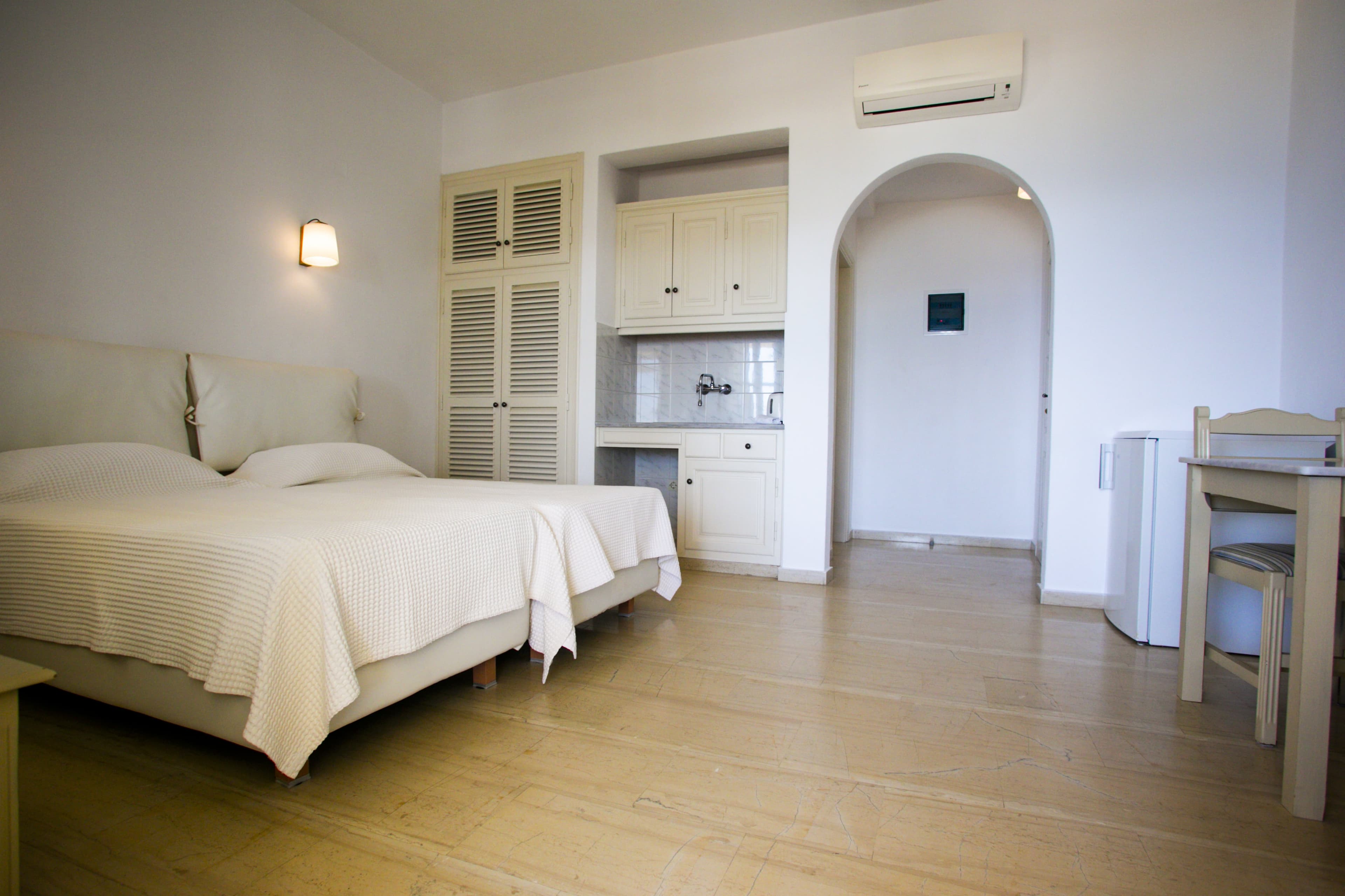 Studio beds beside a kitchenette and arched doorway