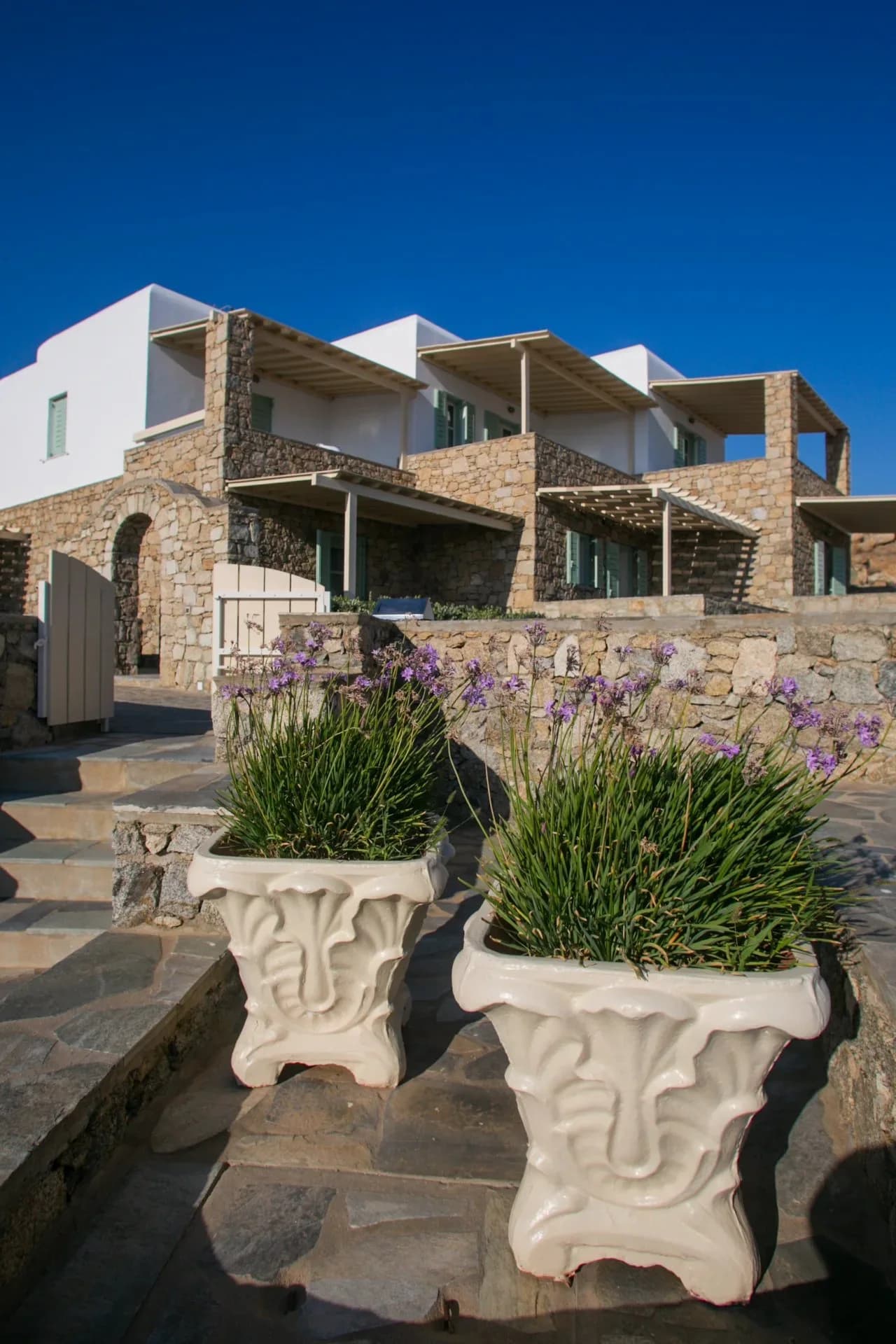 Stone residence buildings behind pots of flowering plants