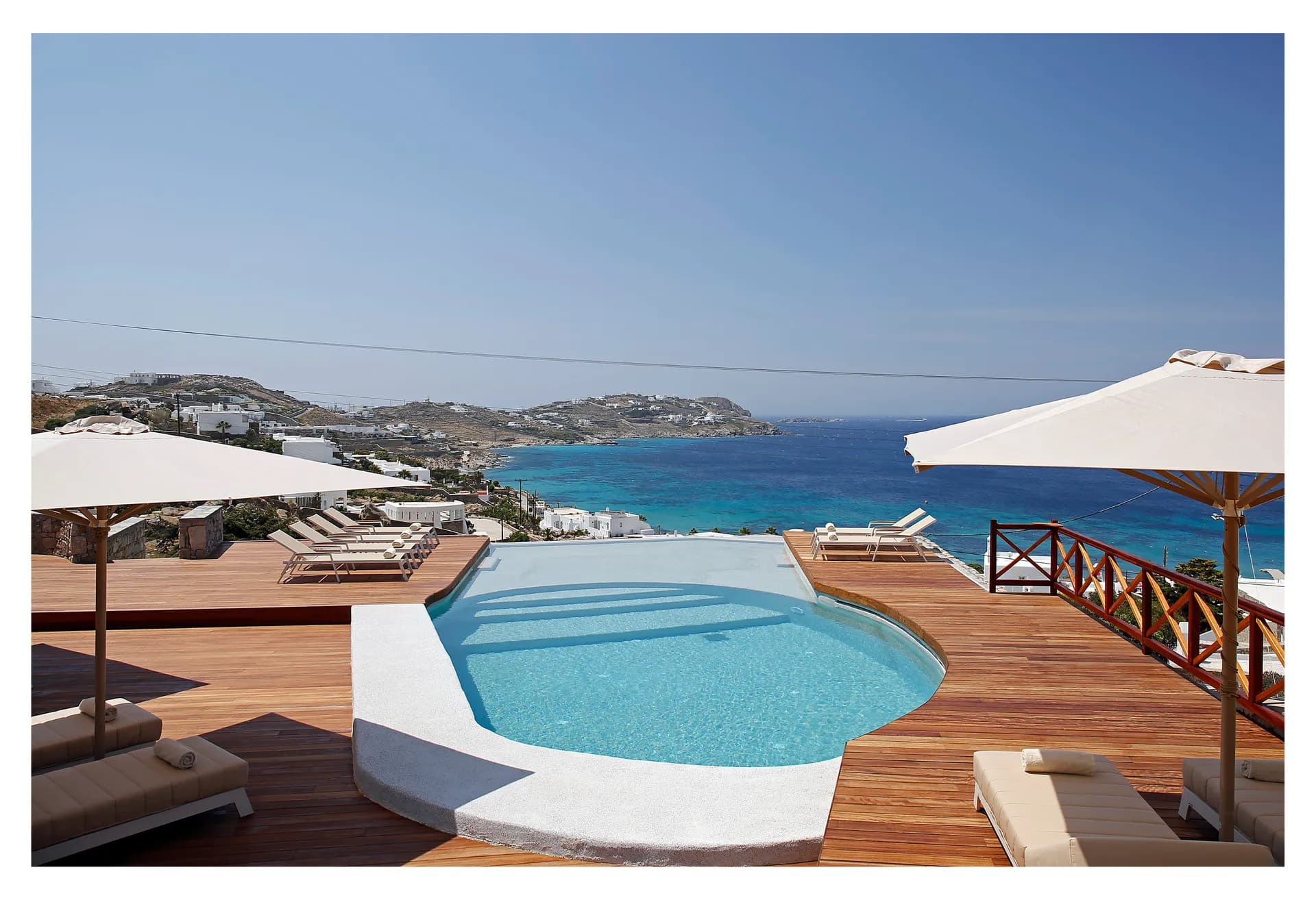 Pool surrounded by parasols and loungers overlooking the bay