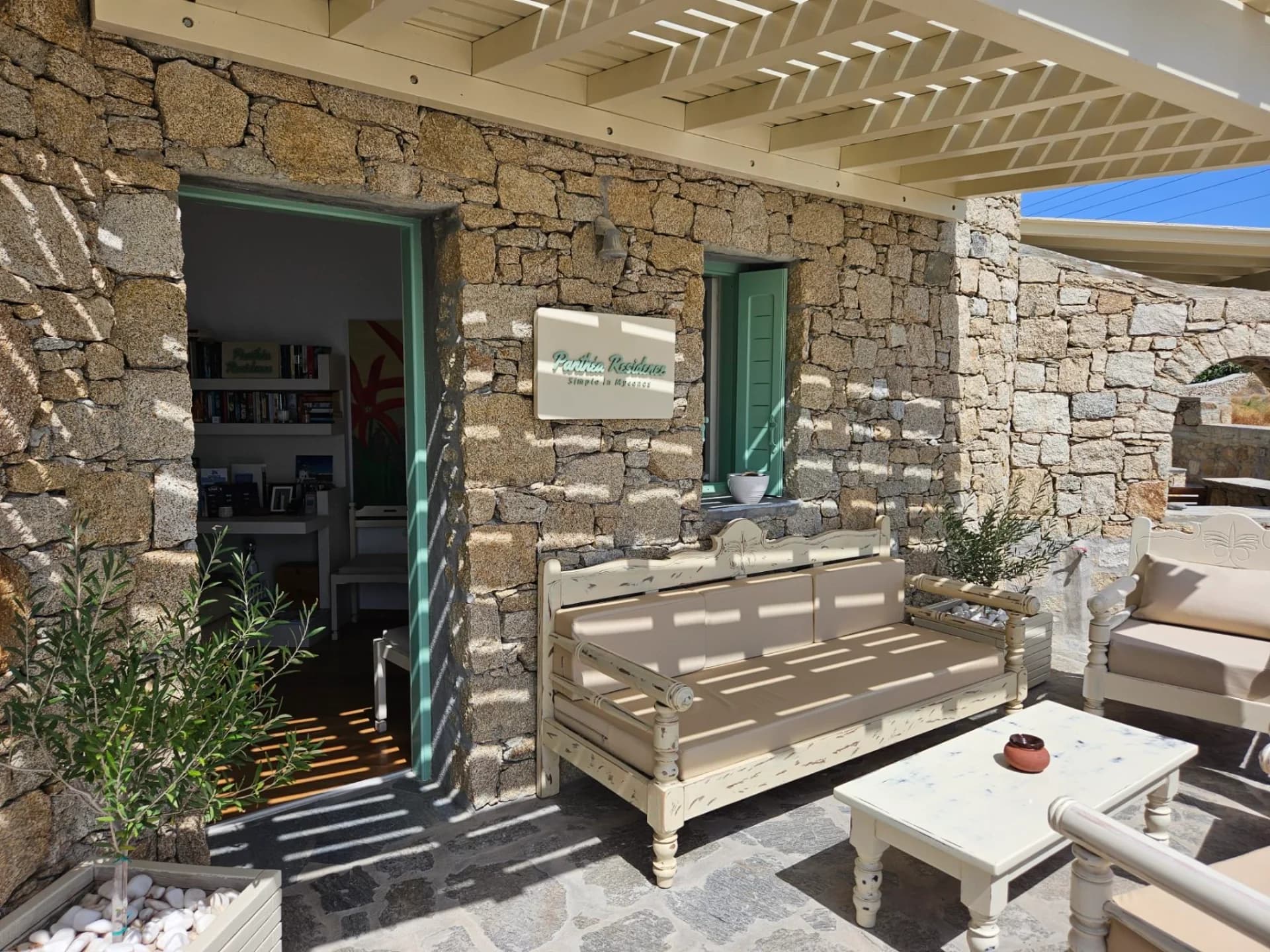 Shaded outdoor seating beside a stone building with green doors