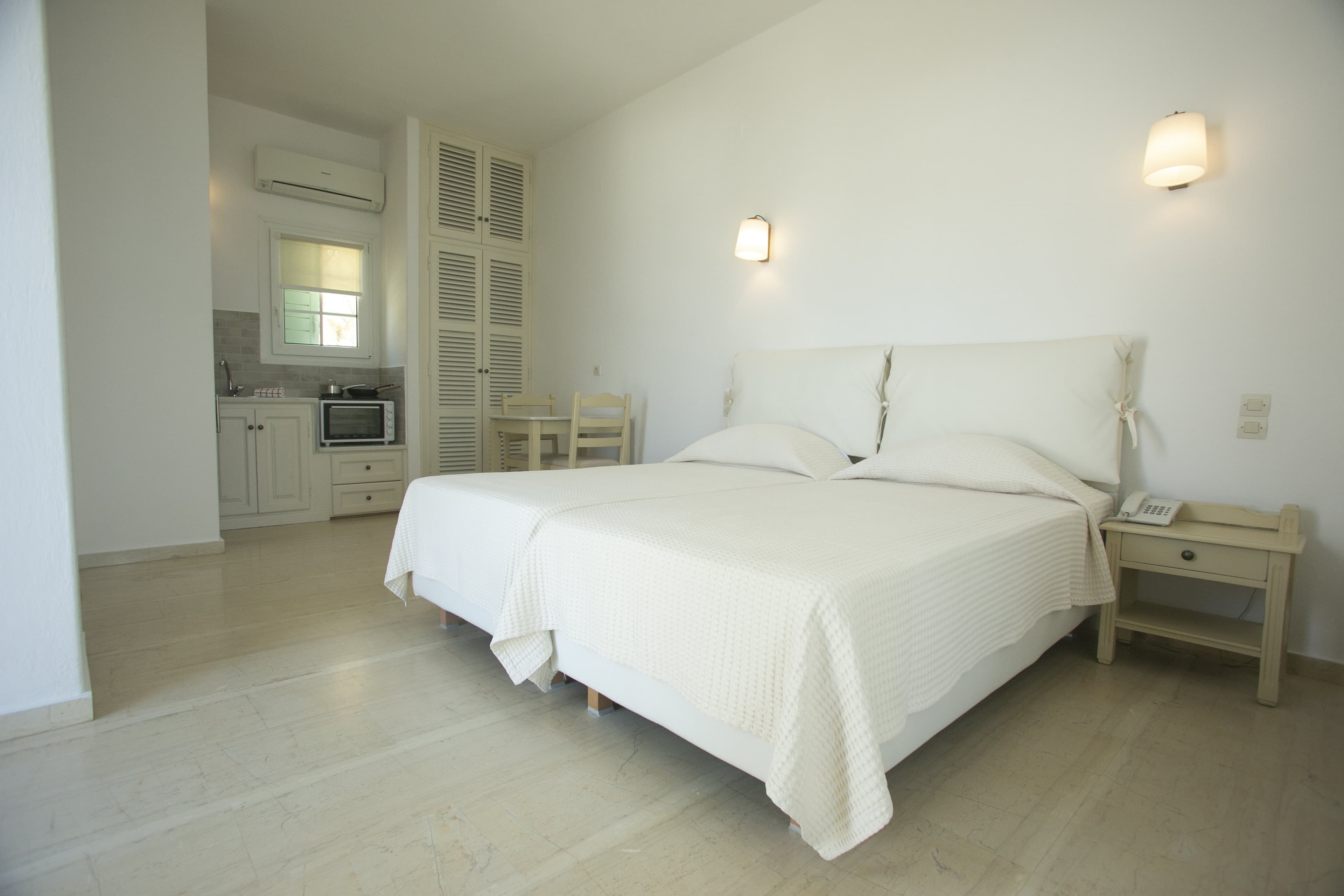 White beds beside the kitchenette in a bright studio