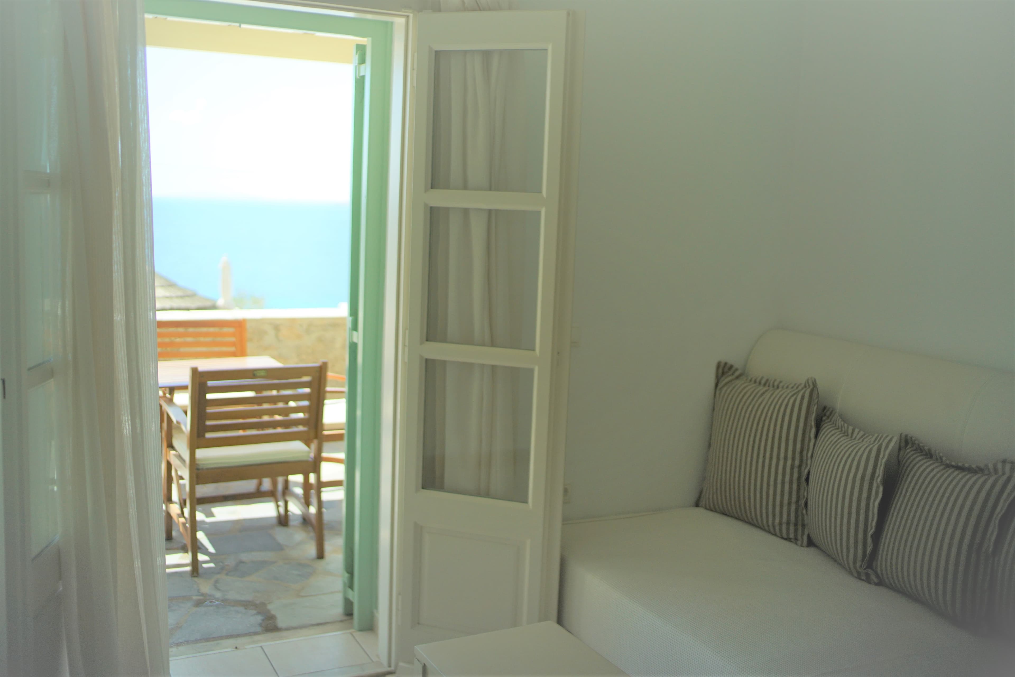 White sofa beside open doors looking toward the sea