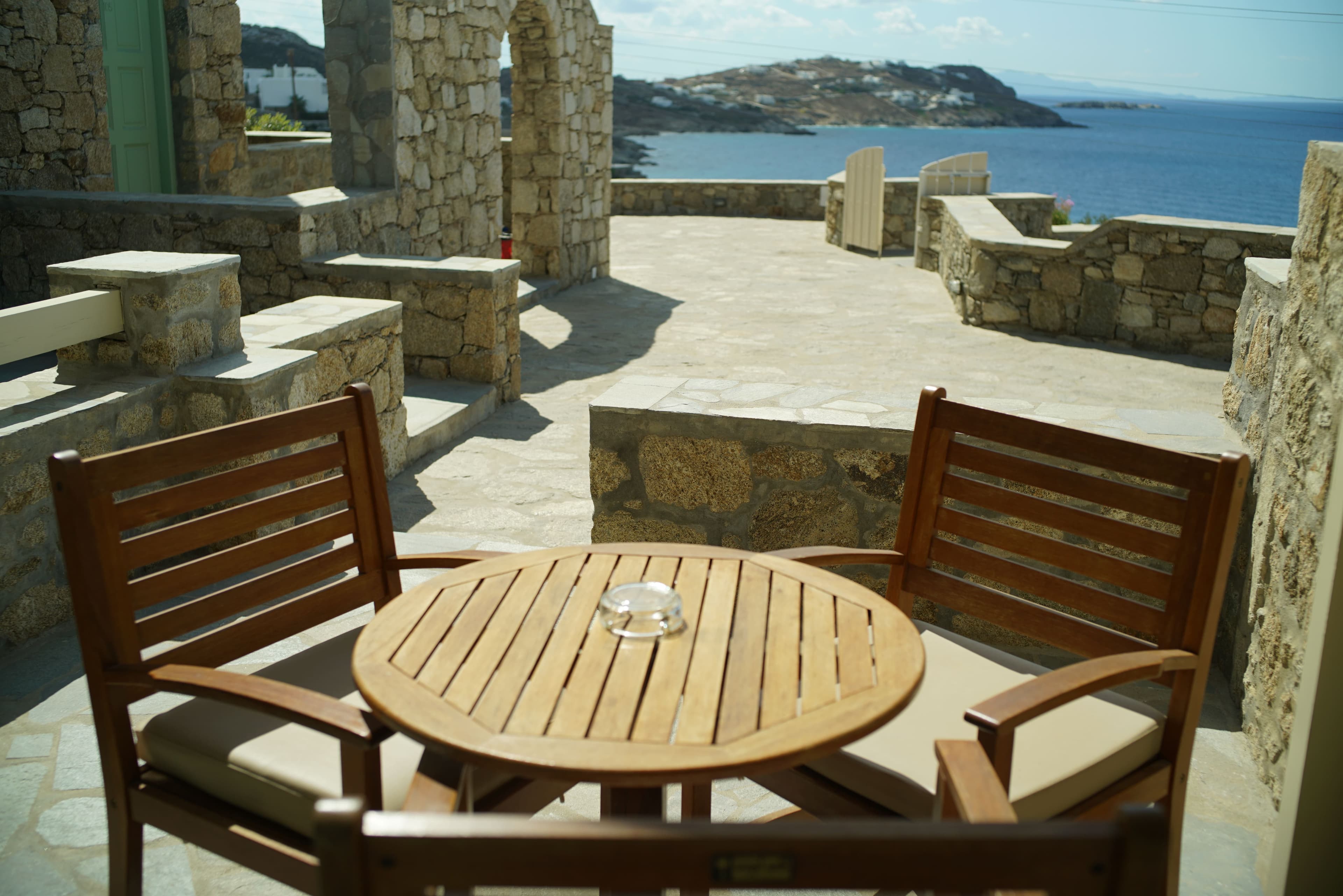 Round outdoor table beside stone paving with the sea beyond